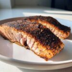 Close-up of two perfectly cooked blackened salmon fillets showing the flaky pink interior and dark spice crust.