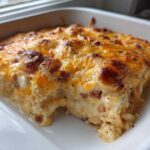 A close-up view of a creamy, baked pierogi casserole topped with melted, browned cheddar cheese.