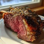 Close-up of a perfectly cooked rib roast showing a medium-rare center and a dark, seasoned crust.