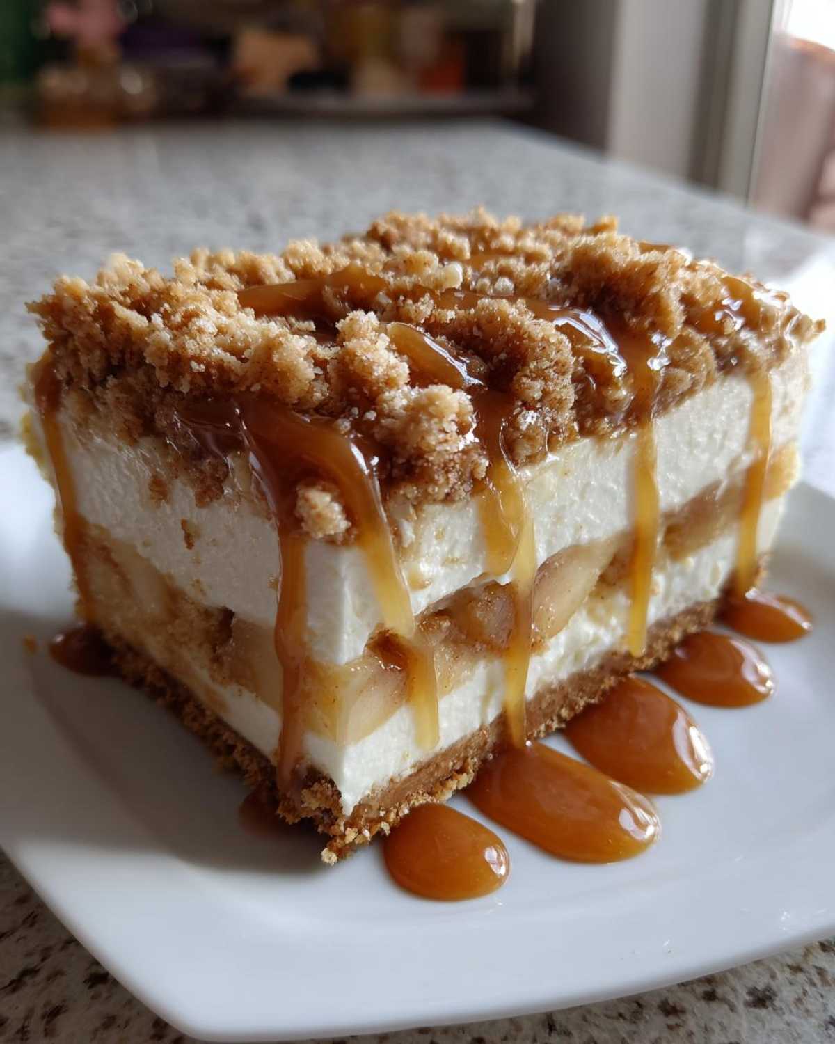 A rich slice of apple pie cheesecake featuring layers of cream cheese, spiced apples, and a crumb topping, drizzled with caramel sauce.