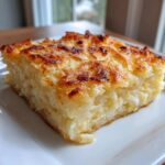 A golden-brown slice of baked cheesy potato casserole with shredded potatoes visible.