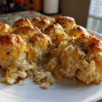 A serving of chicken bubble biscuit bake casserole with golden biscuits and melted cheddar cheese.