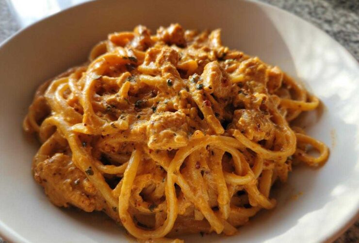 A close-up of creamy Cajun chicken pasta tossed with linguine or spaghetti noodles in a white bowl.