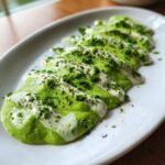 A vibrant green cilantro lime sauce drizzled artistically over a white base, garnished with fresh herbs.