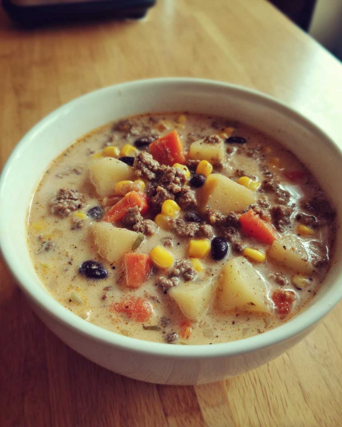 Close-up of a hearty bowl of creamy cowboy soup filled with ground beef, potatoes, corn, and black beans.
