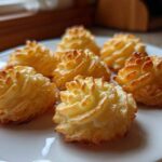 Six perfectly piped and baked duchess potatoes with golden brown, crispy edges served on a white plate.