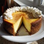 A creamy, baked eggnog cheesecake recipe with a graham cracker crust, topped with whipped cream and cinnamon.