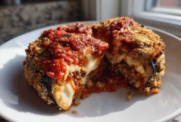 A close-up view of a serving of baked eggplant parmesan, showing melted cheese and marinara sauce.
