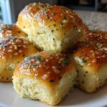 A stack of golden brown sourdough discard rolls brushed with garlic butter and sprinkled with parsley.
