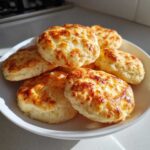 A pile of freshly baked, golden brown 3 ingredient cloud bread puffs served in a white bowl.