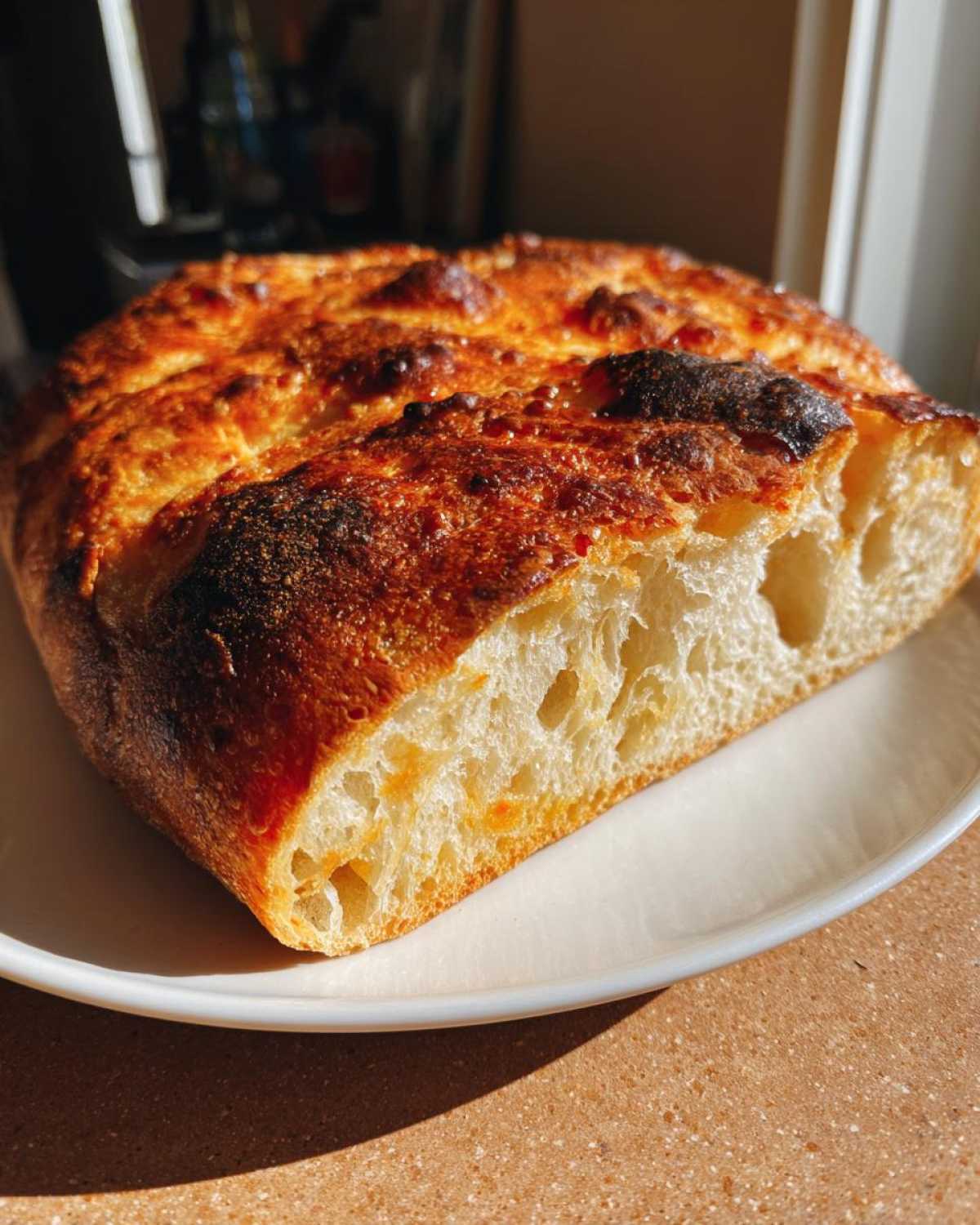 Cross-section of a beautifully baked, airy homemade pizza dough loaf showing a golden crust and open crumb structure.