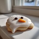 A single melted snowman cookie featuring white icing drip, chocolate chip eyes, and a sugar sprinkle carrot nose.