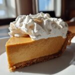 A perfect slice of old-fashioned butterscotch pie with a graham cracker crust and topped with fluffy whipped cream.