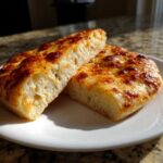 Two thick slices of light, airy homemade pizza dough topped with melted, browned cheese.