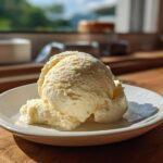 A perfect scoop of creamy, pale yellow banana ice cream served on a small white dish.
