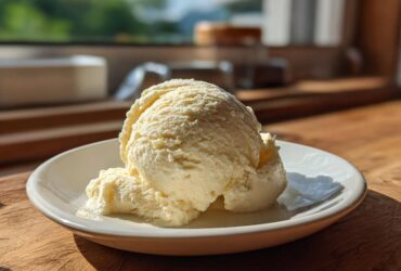 A perfect scoop of creamy, pale yellow banana ice cream served on a small white dish.