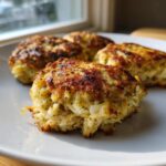 Close-up of four golden-brown, pan-seared maryland crab cakes showing flaky white crab meat inside.