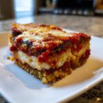 Close-up of a thick, layered slice of baked eggplant parmesan with melted cheese and rich tomato sauce.