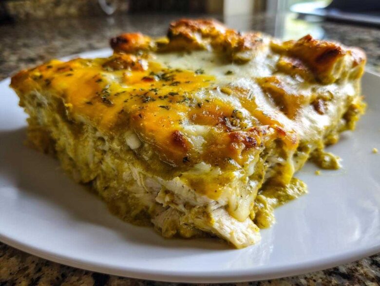 Close-up of a rich, cheesy slice of green chile chicken enchiladas covered in melted cheese and herbs.