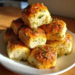 A stack of golden brown sourdough discard rolls brushed with garlic butter and parsley.
