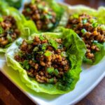 Close-up of savory chicken lettuce wraps filled with ground chicken mixture and topped with fresh green onions.