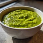 Close-up of thick, bright green broccoli cheddar soup served in a white bowl.