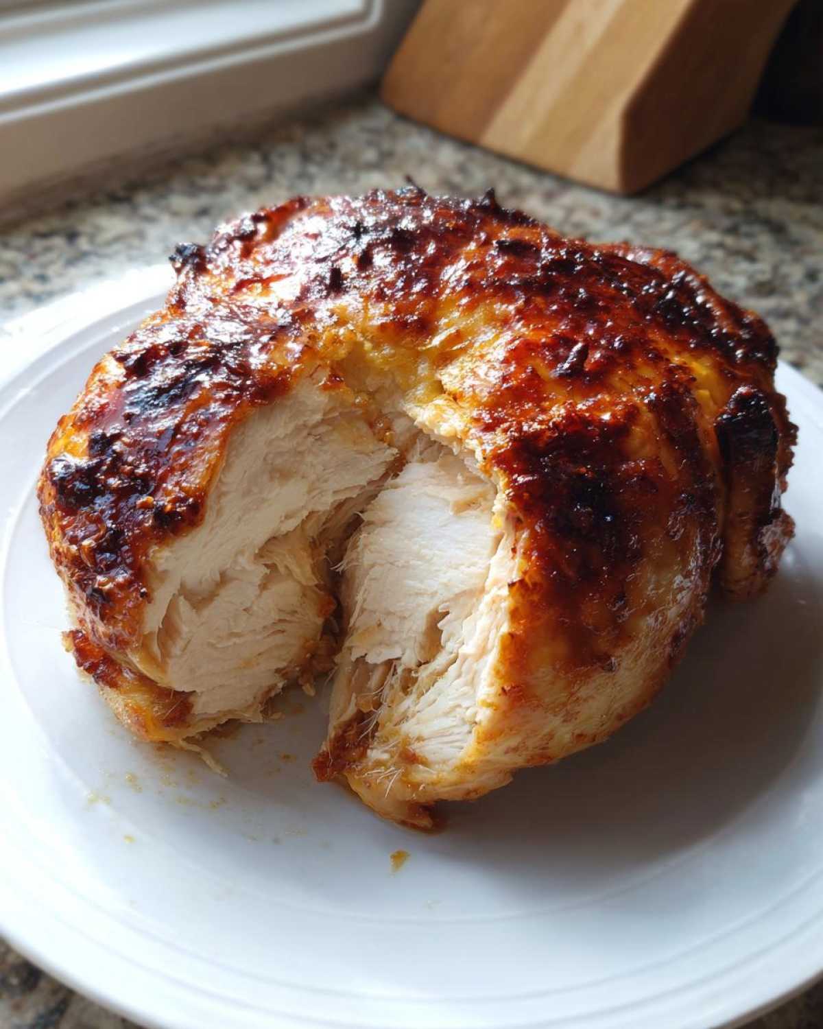 Close-up of a perfectly cooked air fryer whole chicken, split open to show moist white meat and crispy, browned skin.
