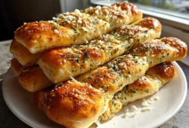 A tempting stack of golden brown, twisted breadsticks topped with garlic, parmesan, and parsley.