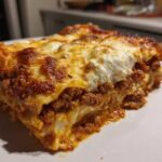 Close-up of a thick, cheesy slice of homemade lasagna with rich meat sauce layers.