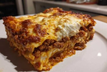 Close-up of a thick, cheesy slice of homemade lasagna with rich meat sauce layers.