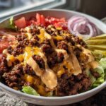 A close-up of a delicious cheeseburger bowl featuring seasoned ground beef, melted cheese, and special sauce over lettuce.
