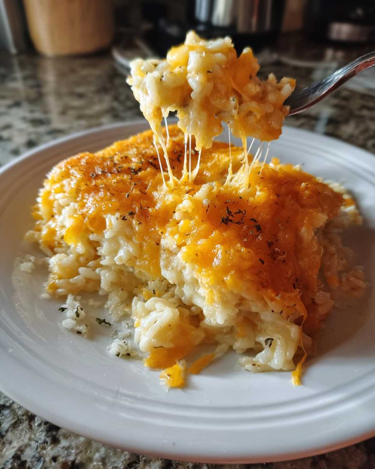 A fork lifting a portion of amazing cheesy rice, showing long, melted cheese strings stretching from the casserole.
