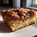 A close-up of a square slice of amazing coffee cake featuring a thick, crumbly cinnamon streusel topping.