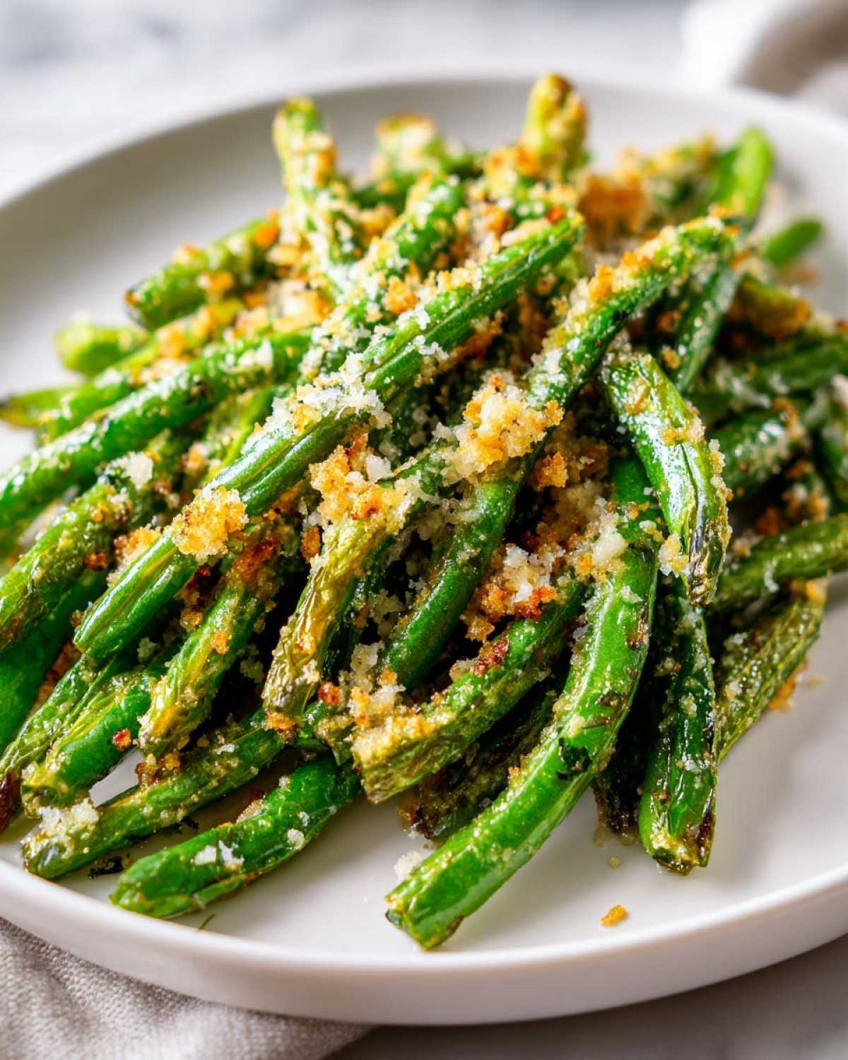Close-up of bright green beans topped with crispy breadcrumbs and Parmesan cheese.