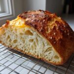 Cross-section of a freshly baked Italian bread showing an open, airy crumb structure resting on a wire rack.