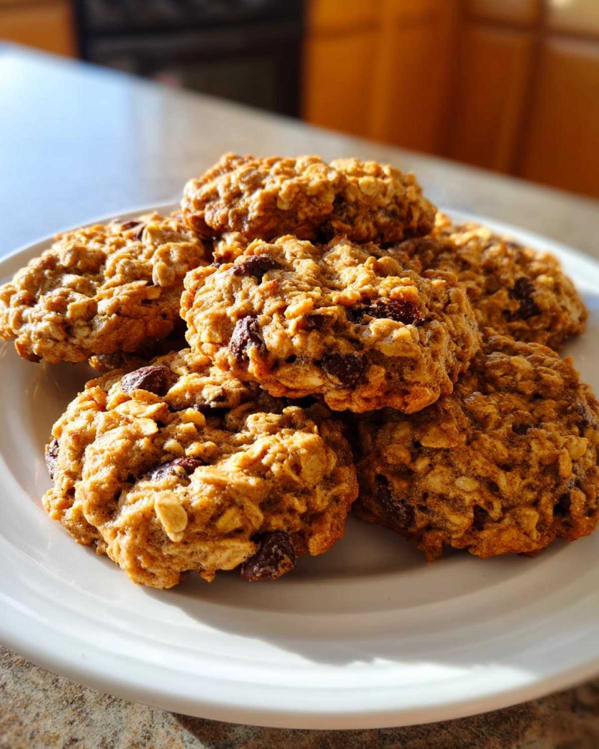A stack of freshly baked, chewy oatmeal cookie treats piled high on a white plate.