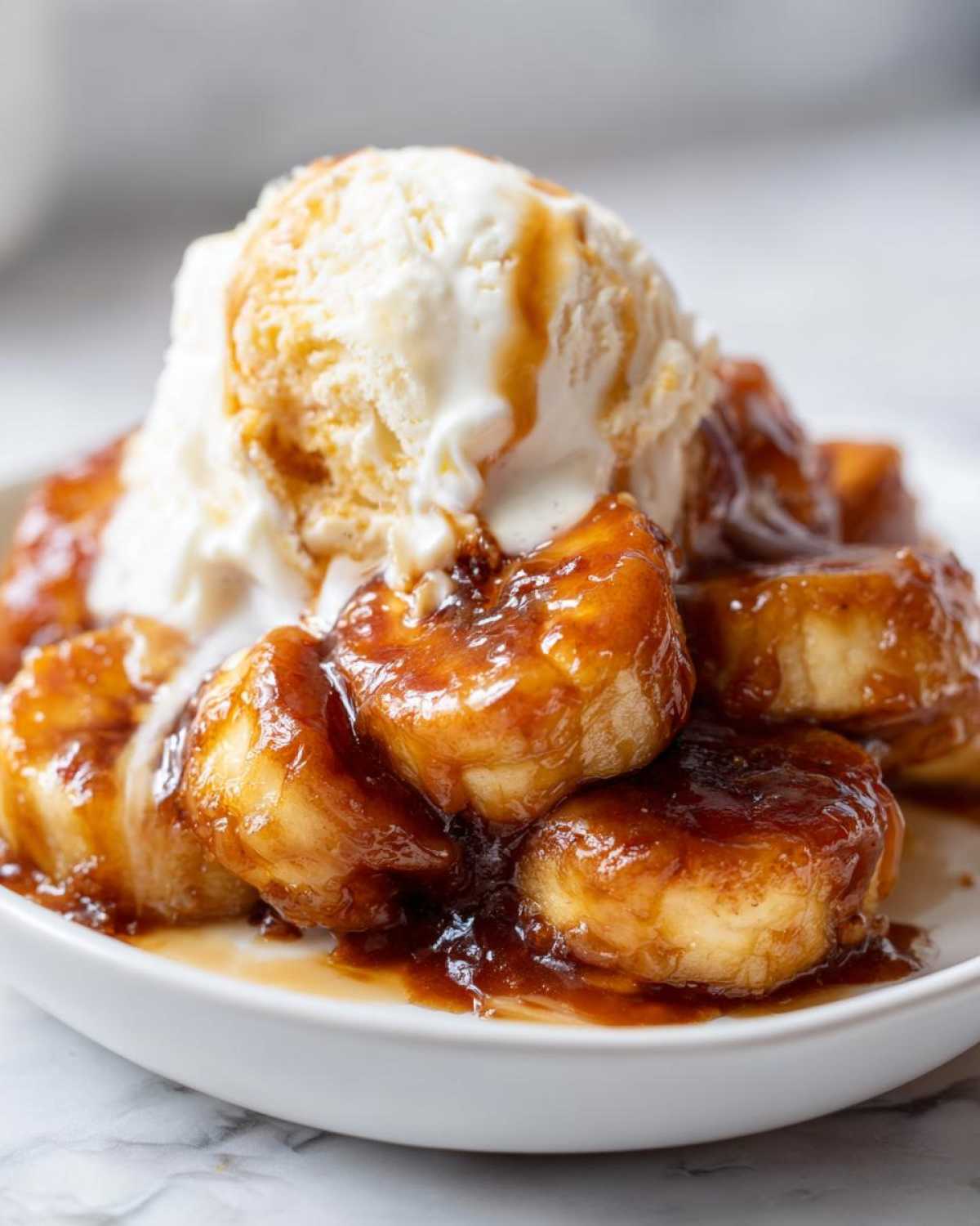Close-up of warm, caramelized bananas foster topped with a scoop of melting vanilla ice cream.
