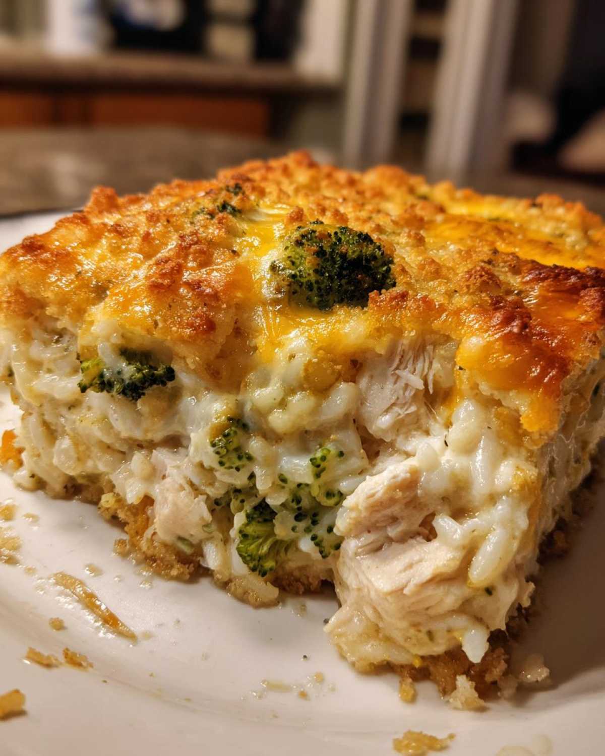 Close-up of a serving of creamy chicken broccoli rice casserole topped with melted cheese and a golden crust.