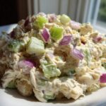 Close-up of creamy cottage cheese chicken salad topped with diced red onion and celery.