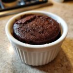Close-up of a rich, dark chocolate Cottage Cheese Microwave Brownie baked perfectly in a white, fluted ramekin.