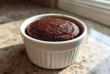 A single, rich, dark brown Cottage Cheese Microwave Brownie baked in a white fluted ramekin.