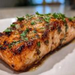 Close-up of a perfectly cooked, crispy air fryer salmon fillet topped with a shiny glaze and fresh parsley.