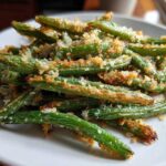 A close-up of crispy, roasted green beans topped with golden parmesan breadcrumbs.