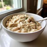 A close-up of a creamy bowl of crockpot white chicken chili, featuring shredded chicken and white beans.