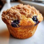 A golden brown, freshly baked blueberry muffin topped with a thick layer of cinnamon sugar streusel topping.