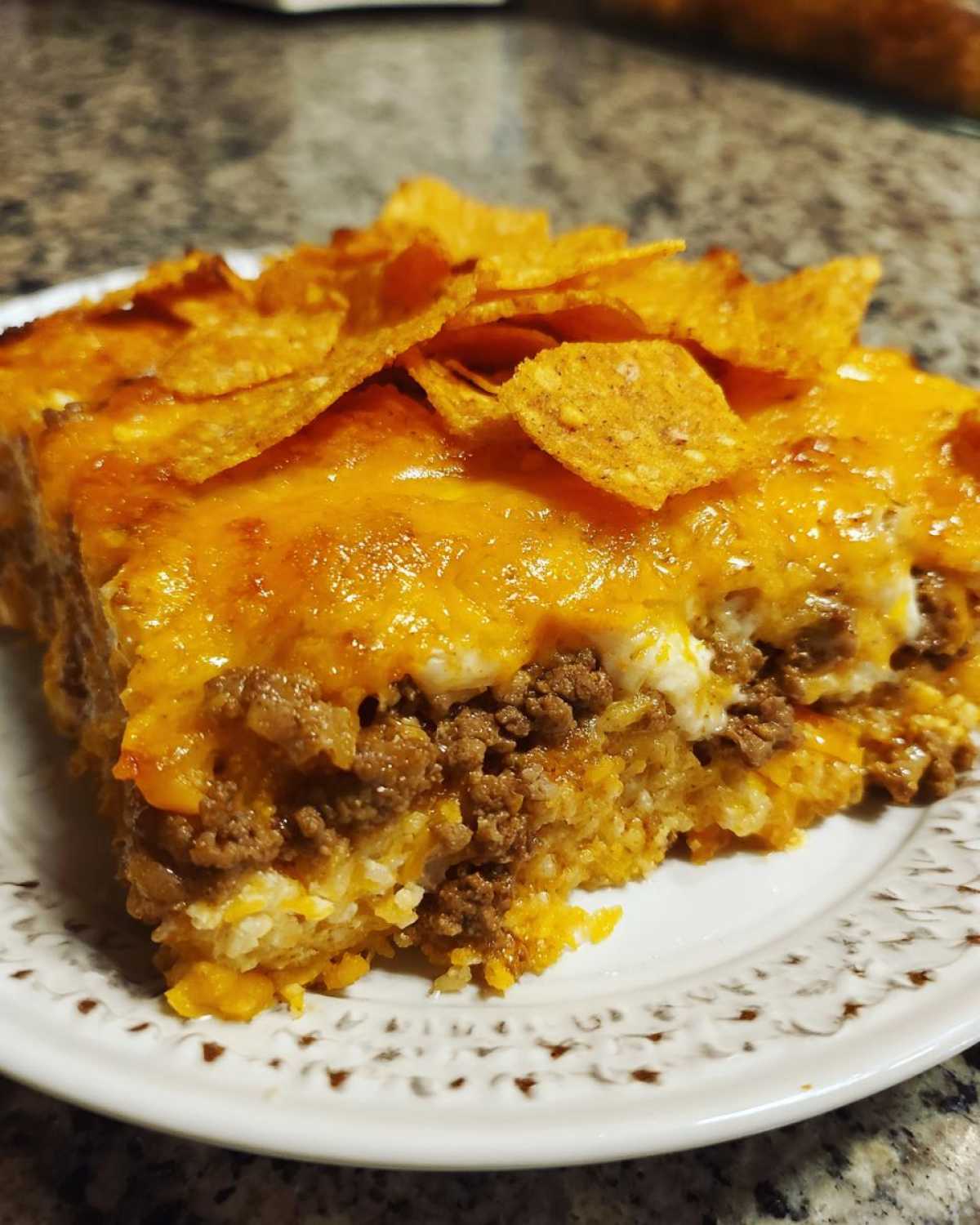 A close-up serving of Dorito Casserole featuring ground beef, cheesy sauce, and crushed Doritos on top.