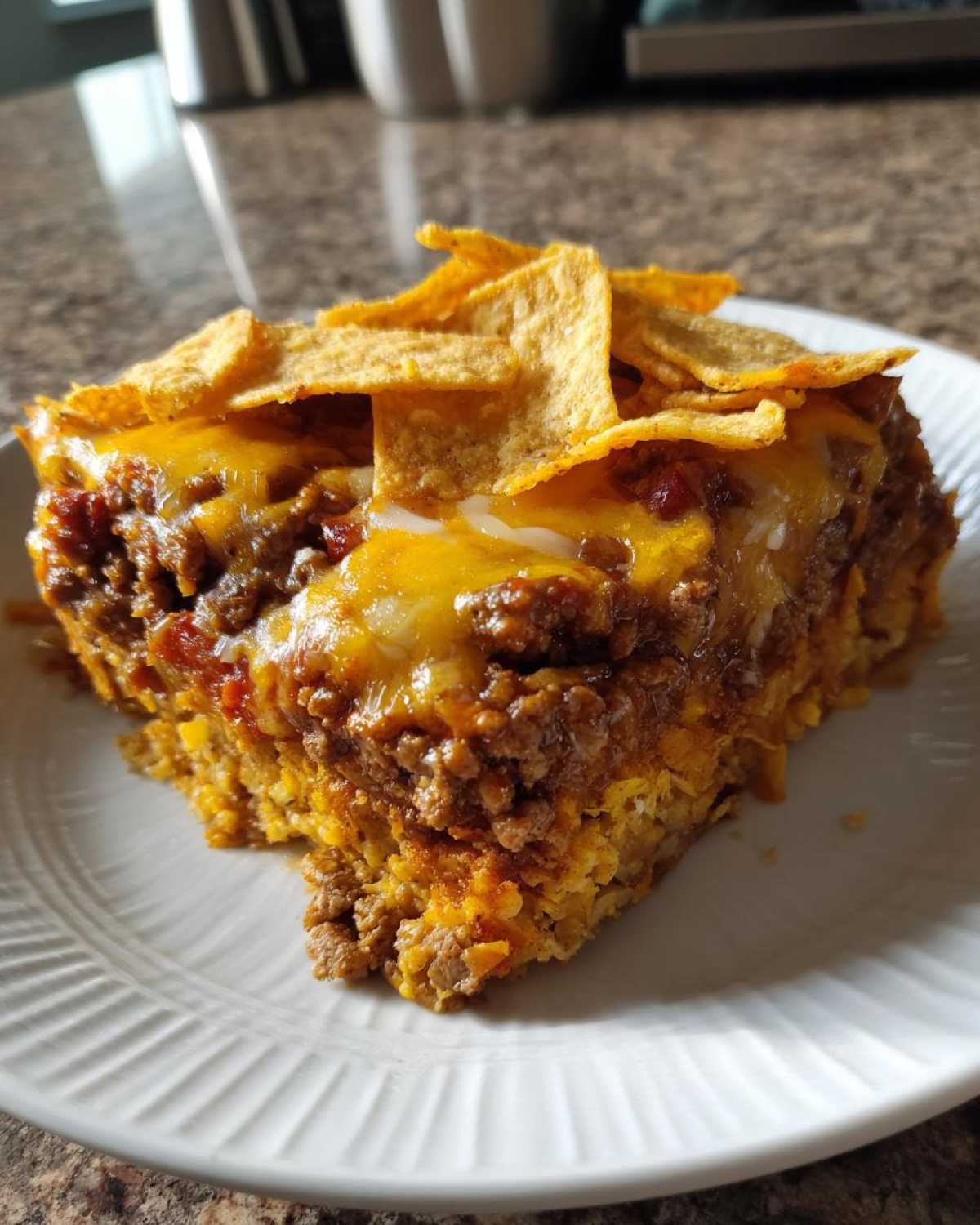A hearty slice of Dorito Casserole topped with melted cheese and crushed tortilla chips.