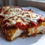 A close-up of two pieces of Easy Chicken Parmesan, showing the crispy breading, bright red sauce, and melted mozzarella cheese.