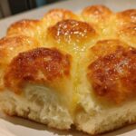 Close-up of freshly baked, golden-brown dinner rolls, glistening with melted butter.