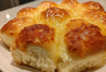 Close-up of freshly baked, golden-brown dinner rolls, glistening with melted butter.